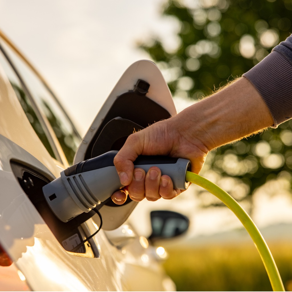 man-inserts-a-power-cord-into-an-electric-car-for-charging-in-the-picture-id1354070884